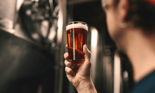 Foto de mão segurando copo com cerveja